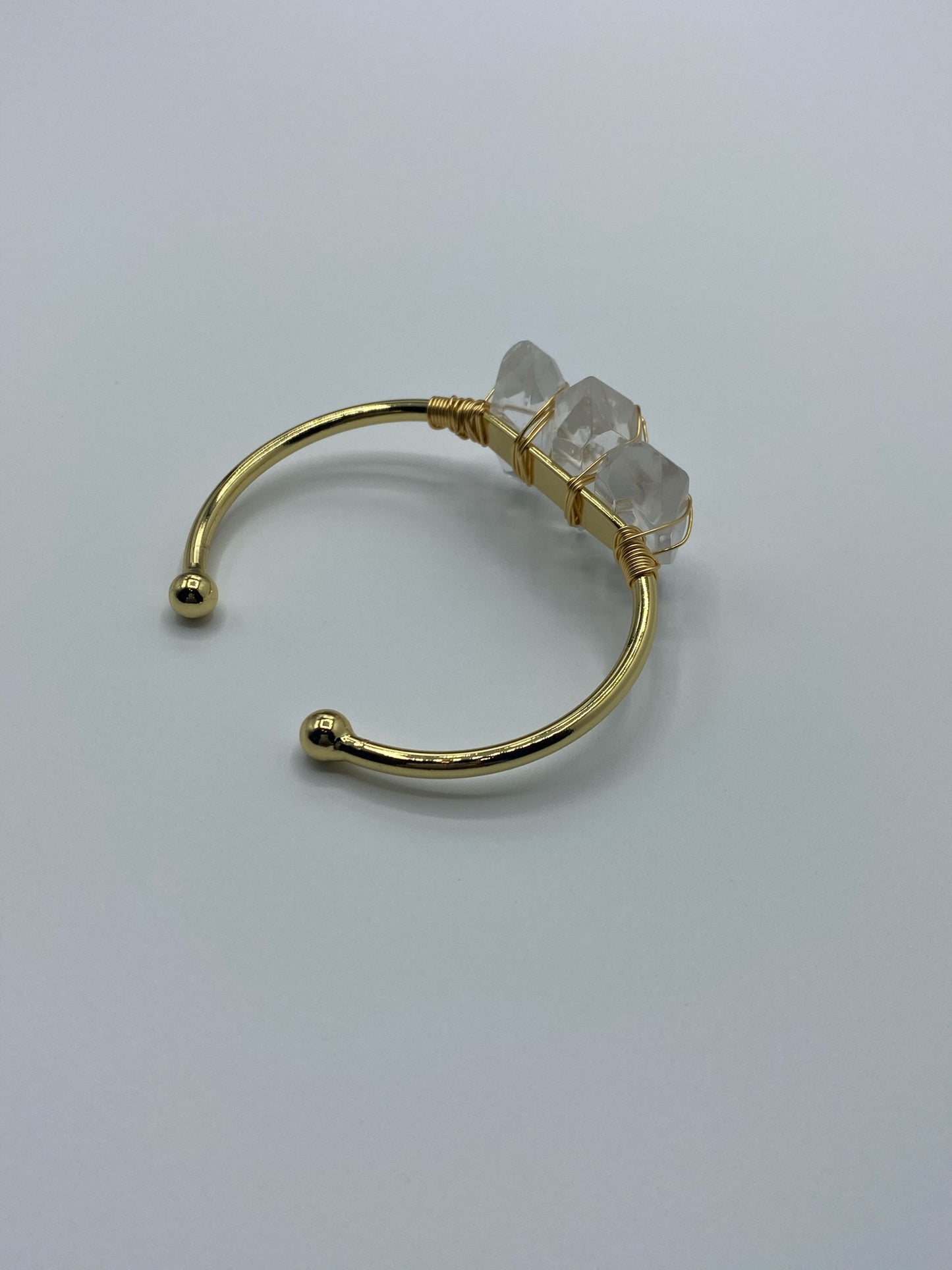 Three small to medium clear quartz crystals on a 18K gold plated bangle.